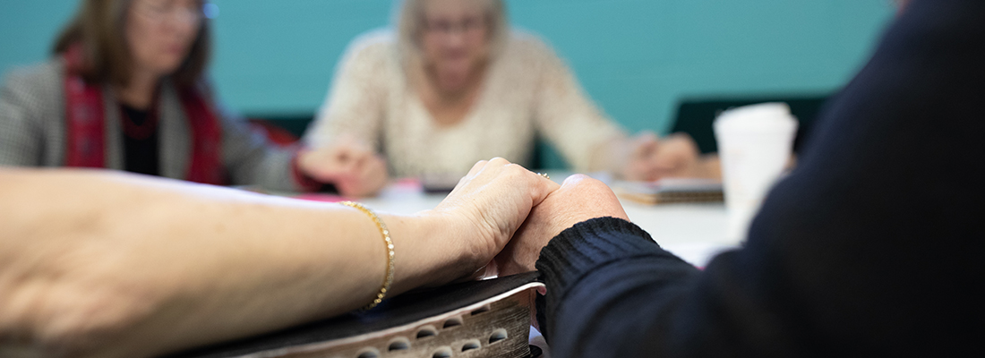 Close up photo of Fair Haven Baptist Church small group members holding hands in prayer.